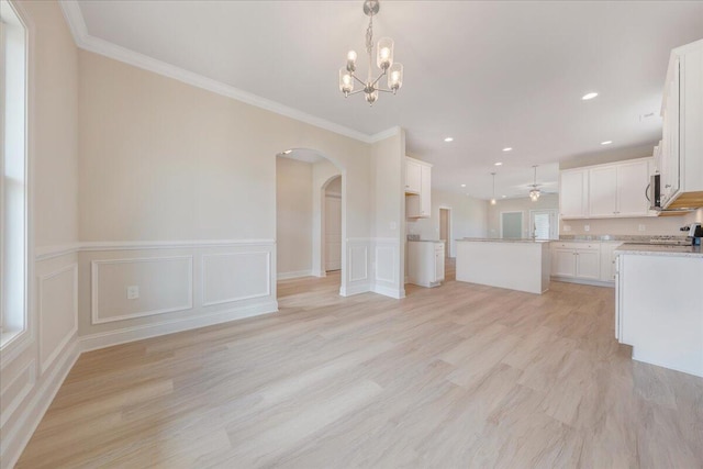 kitchen featuring hanging light fixtures, white cabinetry, open floor plan, and arched walkways