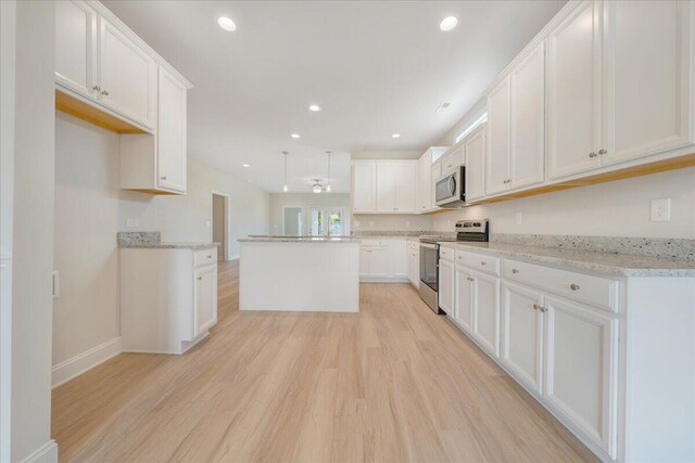 kitchen with hanging light fixtures, white cabinetry, light hardwood / wood-style flooring, and ornamental molding