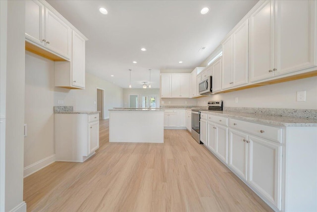 kitchen with appliances with stainless steel finishes, a kitchen island, and white cabinetry