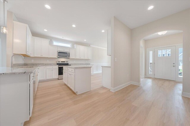 kitchen with white cabinetry, light hardwood / wood-style floors, a center island, and decorative light fixtures