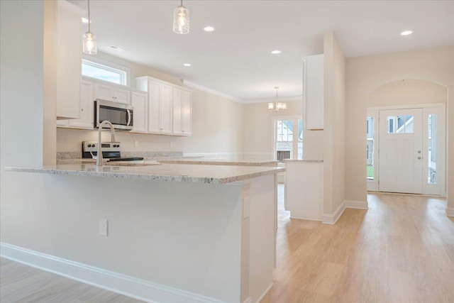 kitchen with light wood-style flooring, decorative light fixtures, a peninsula, stainless steel appliances, and white cabinetry