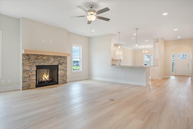 unfurnished living room featuring light wood-style floors, a wealth of natural light, a fireplace, and baseboards