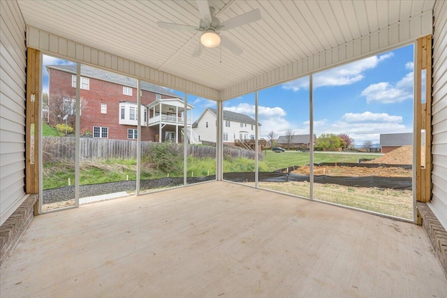 unfurnished sunroom featuring a ceiling fan and a residential view