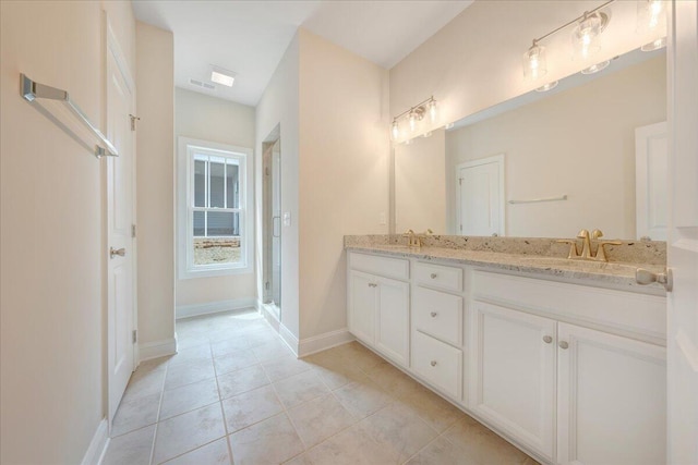 bathroom with tile patterned flooring, a sink, baseboards, and double vanity