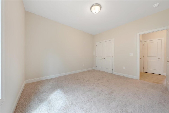 unfurnished bedroom with baseboards, a closet, and light colored carpet