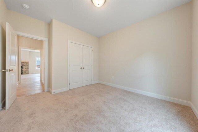 unfurnished bedroom with a closet and light colored carpet