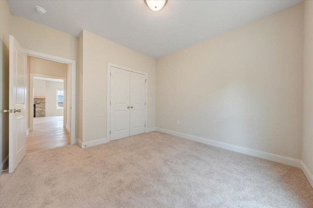 unfurnished bedroom with light carpet, baseboards, and a closet