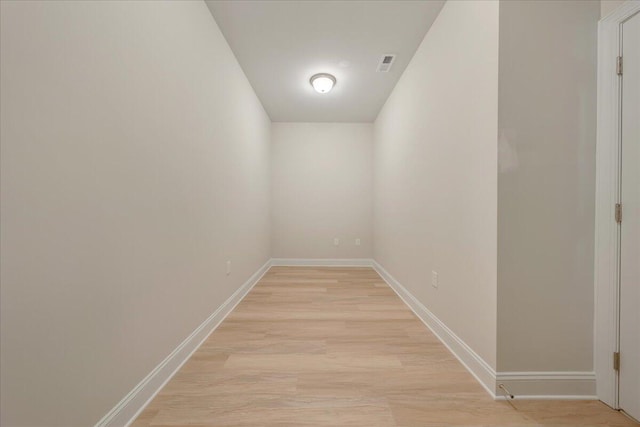 corridor featuring light wood-type flooring, visible vents, and baseboards