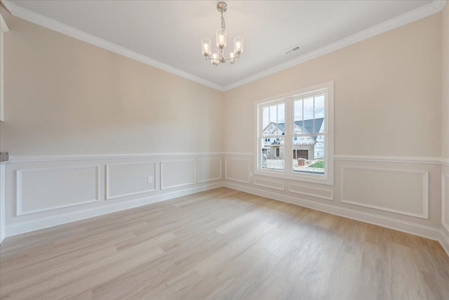 empty room featuring an inviting chandelier, light wood-type flooring, and crown molding