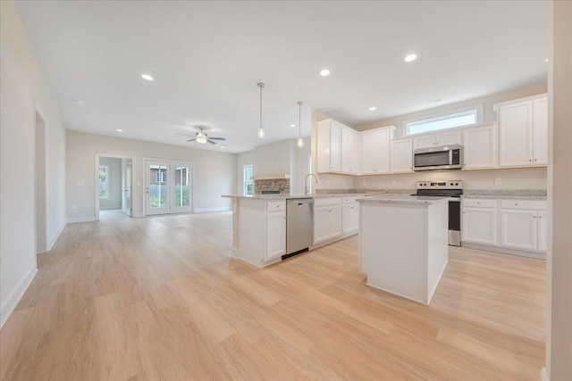 kitchen featuring a peninsula, white cabinetry, stainless steel appliances, and open floor plan