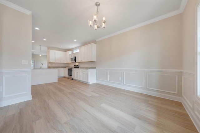 kitchen with white cabinetry, pendant lighting, stainless steel appliances, crown molding, and light hardwood / wood-style flooring