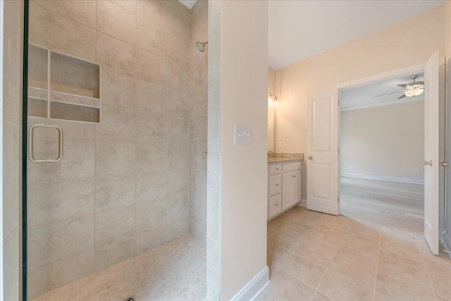 bathroom featuring a ceiling fan, vanity, baseboards, and a stall shower