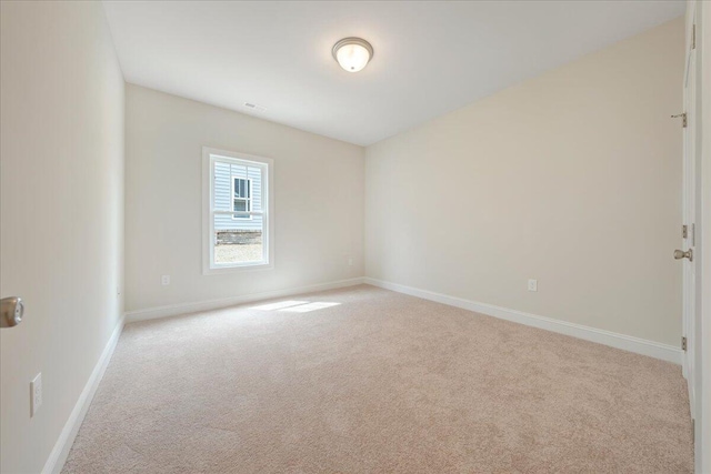 empty room with baseboards, visible vents, and light colored carpet