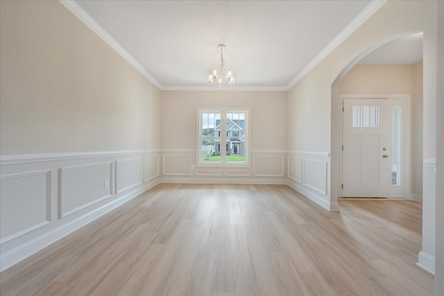 unfurnished dining area with a decorative wall, light wood-type flooring, arched walkways, wainscoting, and a notable chandelier