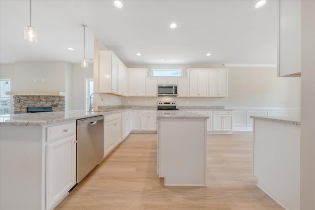 kitchen with a peninsula, light wood-type flooring, stainless steel appliances, and white cabinets
