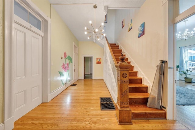 entryway featuring an inviting chandelier, light hardwood / wood-style floors, and high vaulted ceiling