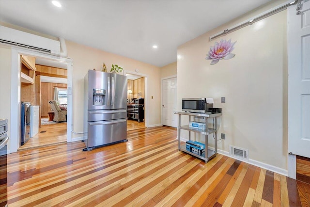 interior space featuring a wall mounted air conditioner, light wood-type flooring, and washer and dryer