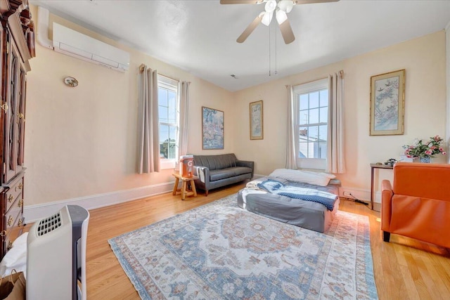 sitting room featuring an AC wall unit, a wealth of natural light, light hardwood / wood-style floors, and ceiling fan