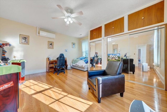 bedroom with a closet, ceiling fan, a wall mounted air conditioner, and hardwood / wood-style flooring