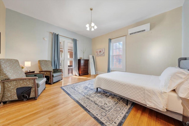 bedroom featuring an inviting chandelier, hardwood / wood-style floors, and a wall mounted air conditioner