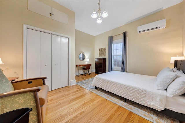 bedroom with an AC wall unit, a chandelier, a closet, and hardwood / wood-style flooring