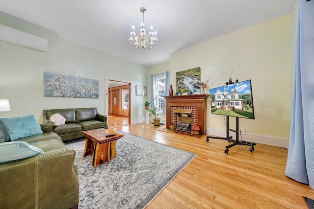 living room with wood-type flooring, a chandelier, a wall unit AC, and a brick fireplace