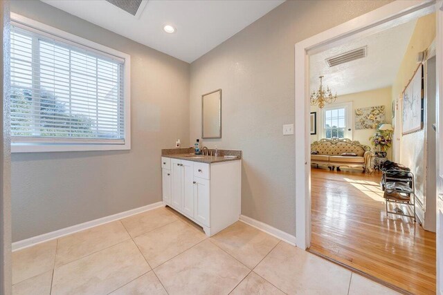 bathroom with an inviting chandelier, wood-type flooring, and vanity