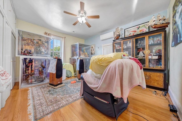 sitting room featuring light wood-type flooring, ceiling fan, and a wall mounted air conditioner