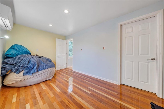 bedroom with an AC wall unit and hardwood / wood-style flooring