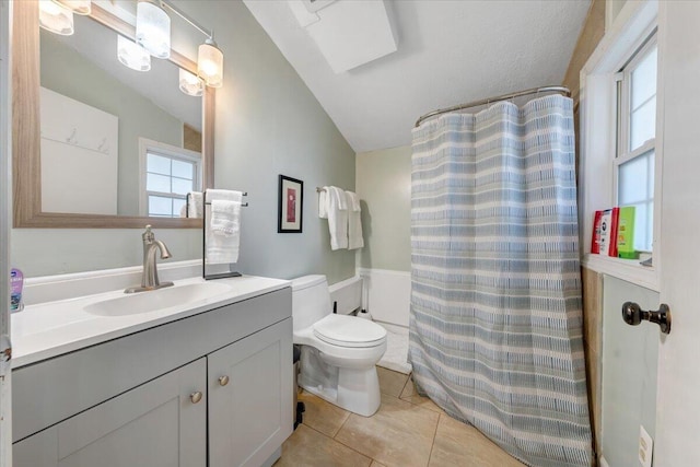 full bathroom with shower / bathtub combination with curtain, vanity, lofted ceiling with skylight, tile patterned flooring, and toilet