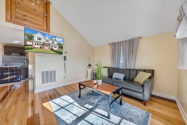 living room with high vaulted ceiling and light hardwood / wood-style floors