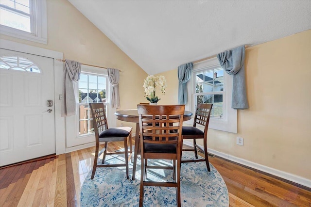 dining area with light hardwood / wood-style flooring and high vaulted ceiling