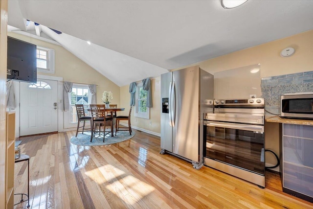 kitchen with light hardwood / wood-style floors, appliances with stainless steel finishes, and vaulted ceiling