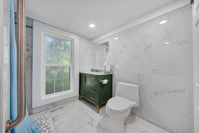 bathroom with vanity, tile walls, and toilet