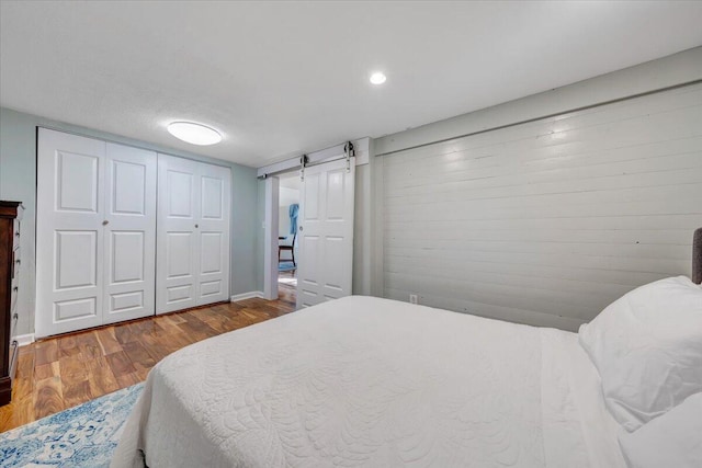 bedroom featuring a closet, hardwood / wood-style floors, and a barn door