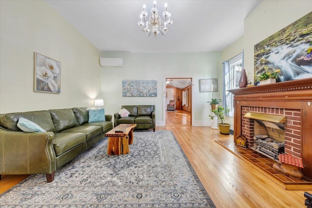 living room featuring a fireplace, an inviting chandelier, a wall mounted AC, and hardwood / wood-style flooring