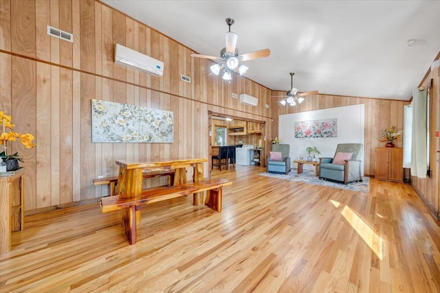 living room featuring ceiling fan, wooden walls, light hardwood / wood-style flooring, and high vaulted ceiling