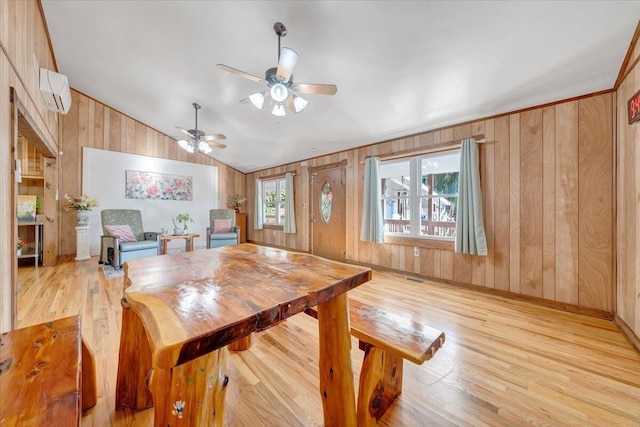 dining room with vaulted ceiling, light hardwood / wood-style floors, wood walls, and ceiling fan