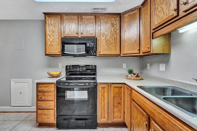 kitchen featuring black appliances, light tile patterned floors, and sink