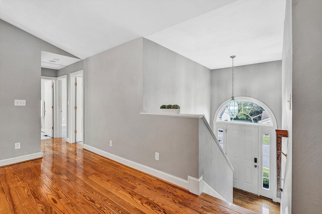 entrance foyer featuring a notable chandelier, vaulted ceiling, and hardwood / wood-style flooring