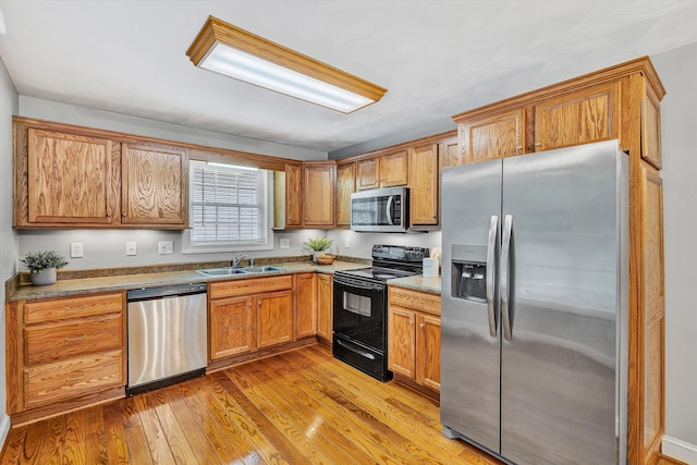 kitchen with appliances with stainless steel finishes, light hardwood / wood-style floors, and sink