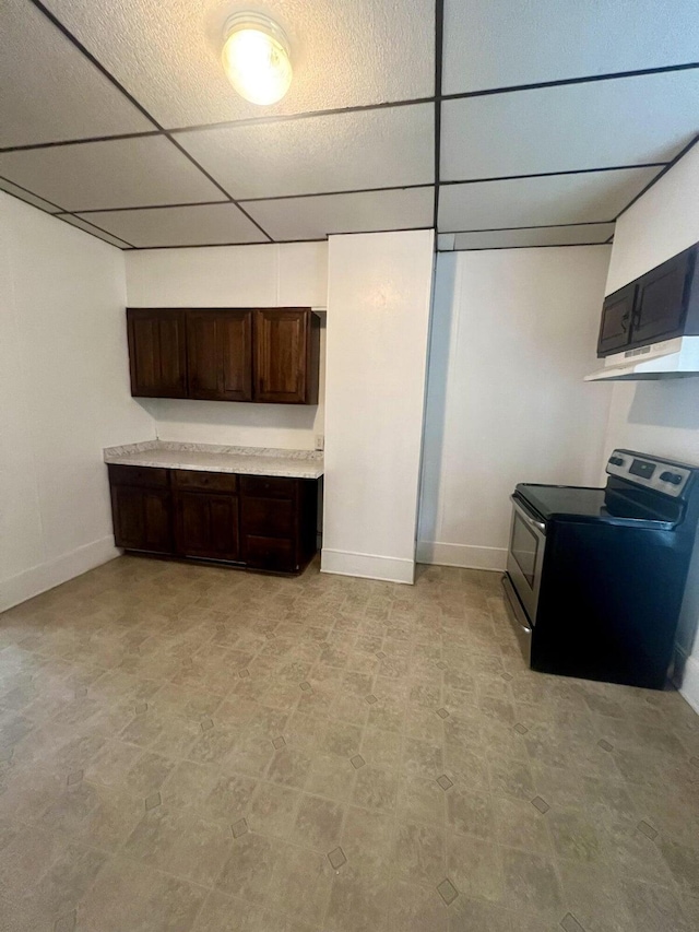 kitchen with a paneled ceiling, light tile patterned flooring, dark brown cabinets, and electric range