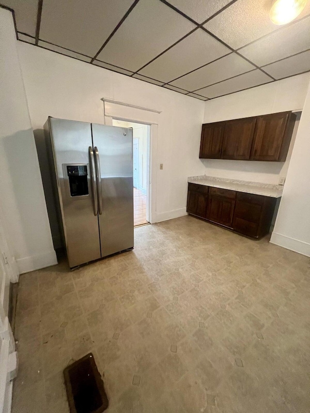 kitchen with dark brown cabinets, stainless steel refrigerator with ice dispenser, and a paneled ceiling