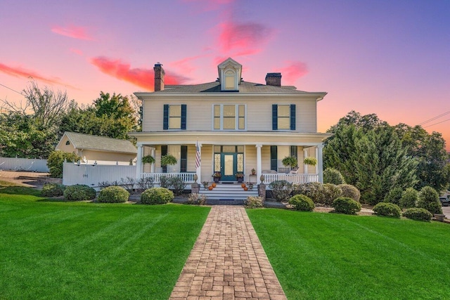 back house at dusk with a lawn and a porch