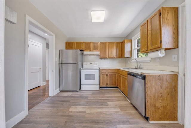 kitchen with appliances with stainless steel finishes, light hardwood / wood-style flooring, and sink