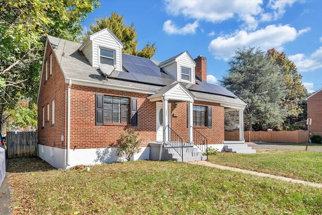 cape cod home featuring solar panels and a front yard