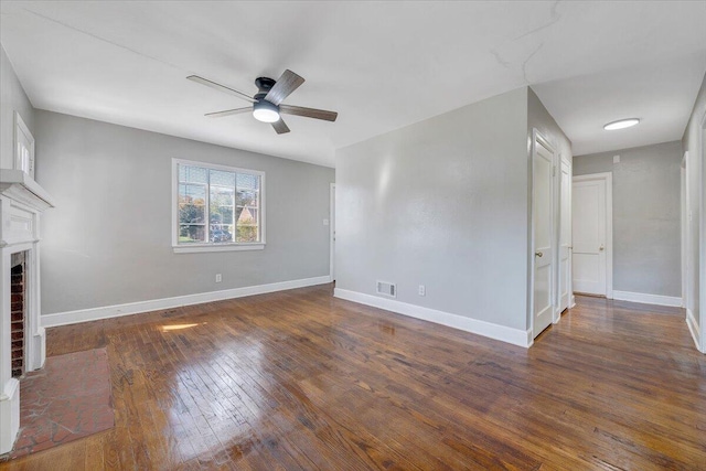 unfurnished living room with ceiling fan, a brick fireplace, and dark hardwood / wood-style floors