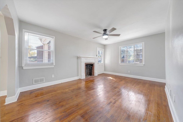 unfurnished living room featuring a healthy amount of sunlight, wood-type flooring, and ceiling fan