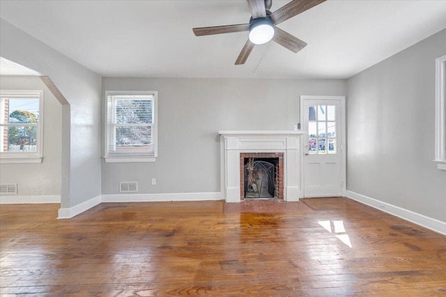 unfurnished living room featuring a brick fireplace, hardwood / wood-style flooring, and ceiling fan