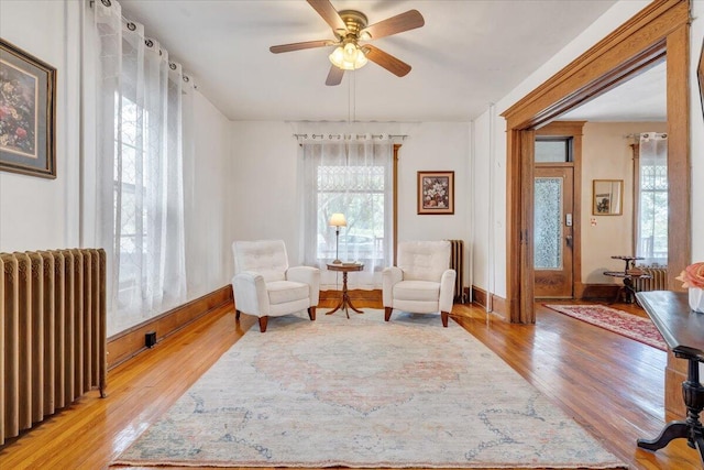 sitting room featuring radiator heating unit, light wood-type flooring, and ceiling fan